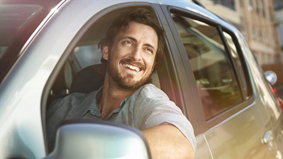 A man smiling while driving his Renault car