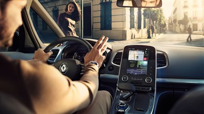 A inside picture of a man captured from backseat while driving his Renault car